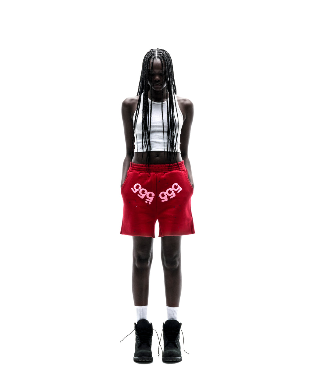 Model in red 13oz cotton fleece Angel Number shorts with white print, drawcord, and raw hem.