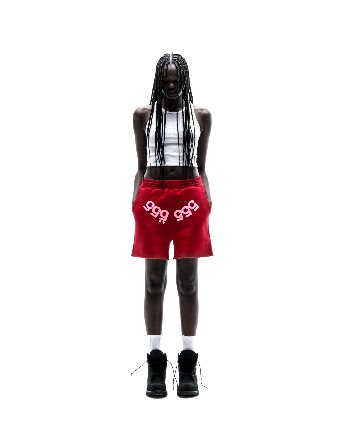 Model in red 13oz cotton fleece Angel Number shorts with white print, drawcord, and raw hem.