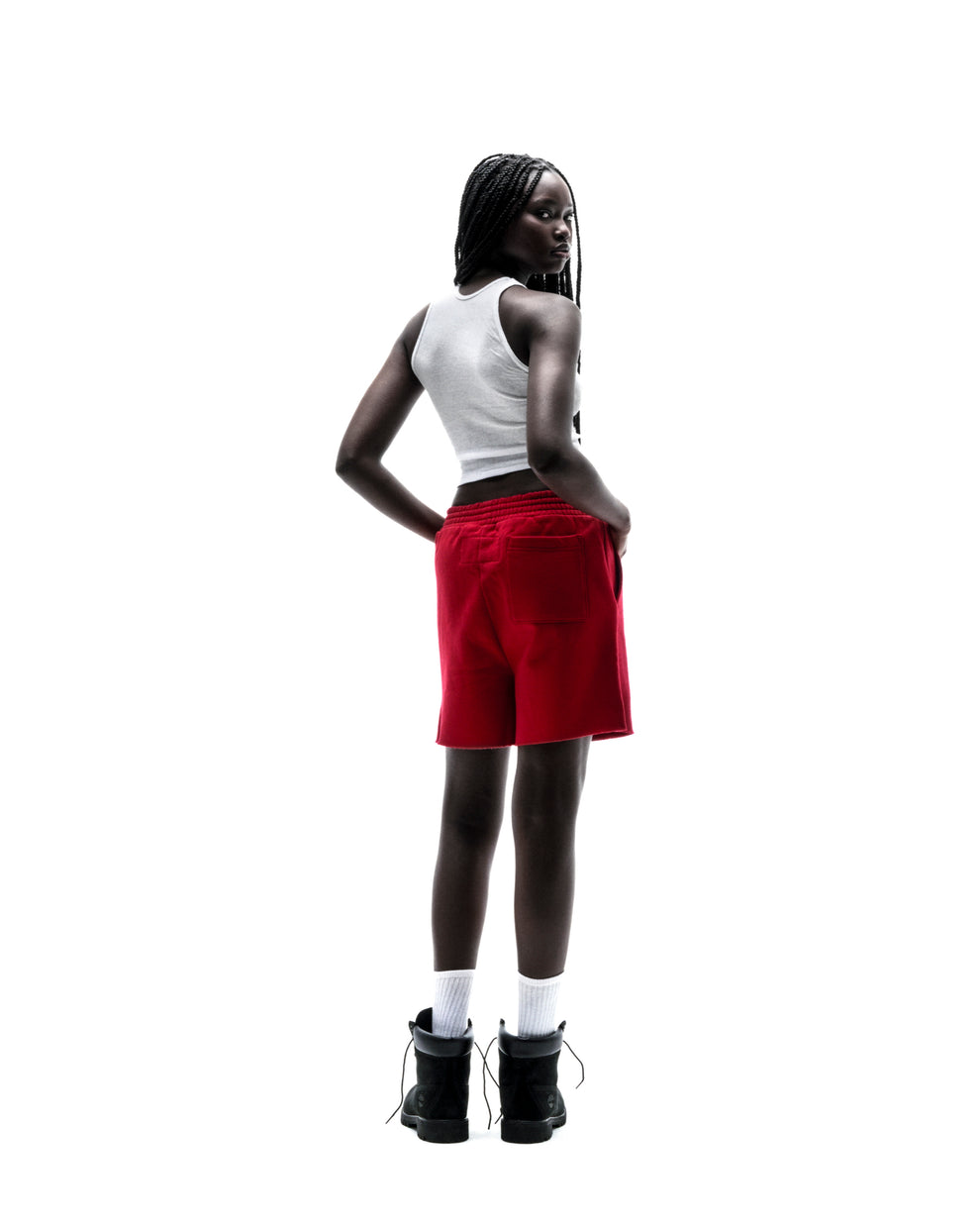 Model in red Angel Number brushed fleece shorts with raw hem, back pocket, and drawcord waistband.
