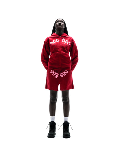Model wears red ANGEL NUMBER ZIP HOODIE and matching shorts with puff print and scattered stars.