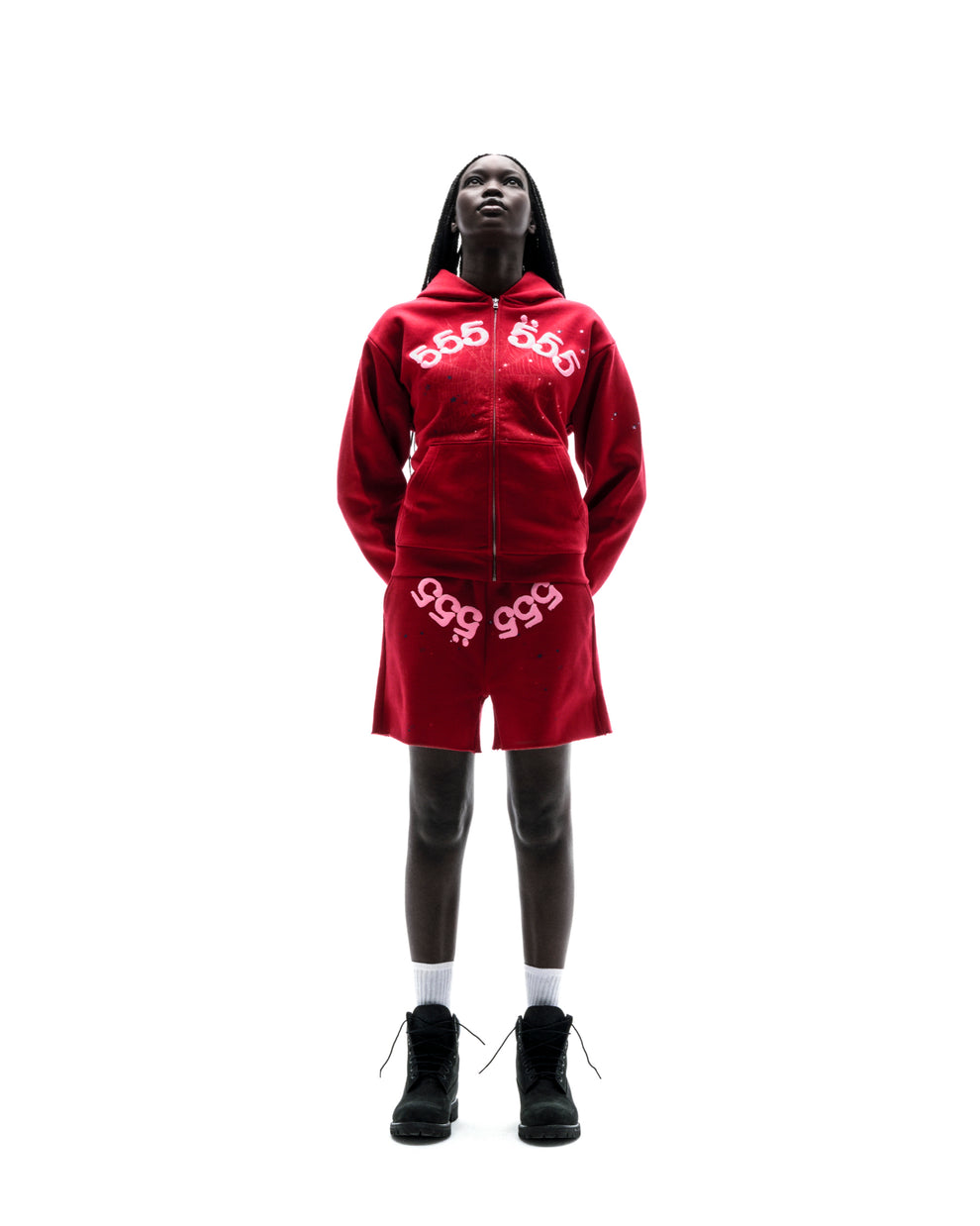 Model wears red ANGEL NUMBER ZIP HOODIE and matching shorts with puff print and scattered stars.