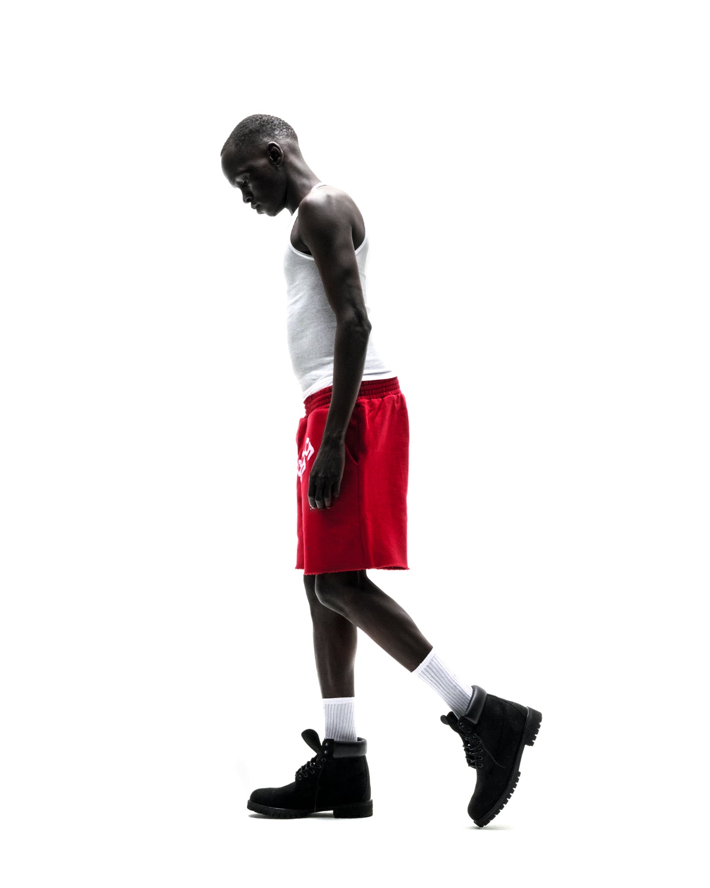 Model wearing red ANGEL NUMBER SHORT with white tank top and black boots.