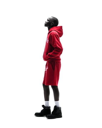 Model in red ANGEL NUMBER ZIP HOODIE and matching shorts with white puff print.