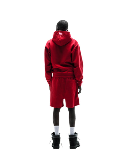 Model from behind wearing a red cotton fleece zip hoodie with a white logo on the hood and matching shorts.