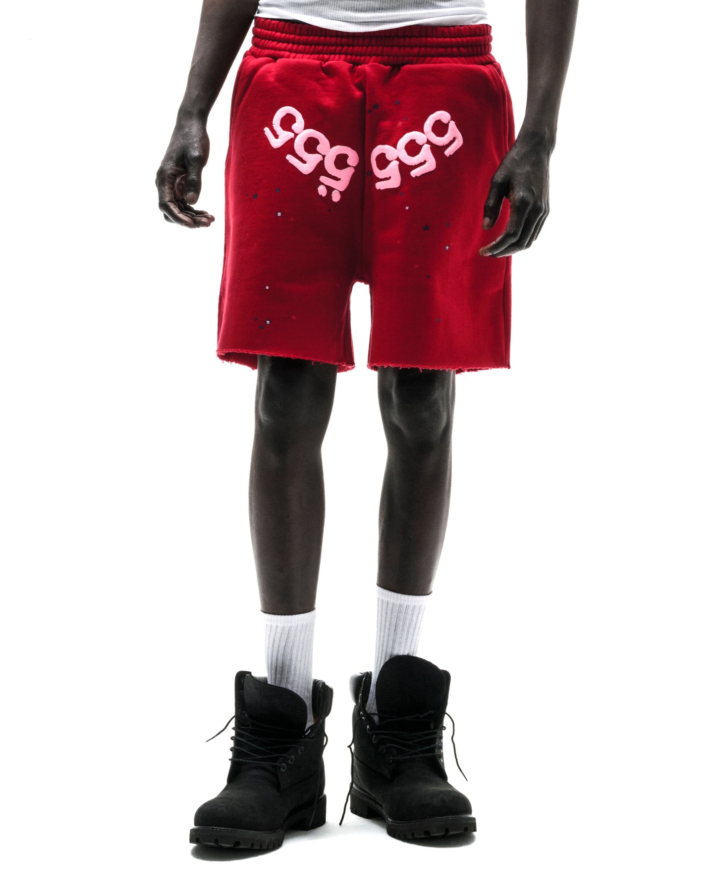 Model wearing red 100% cotton brushed fleece shorts with pink "555" angel number print and raw hem.