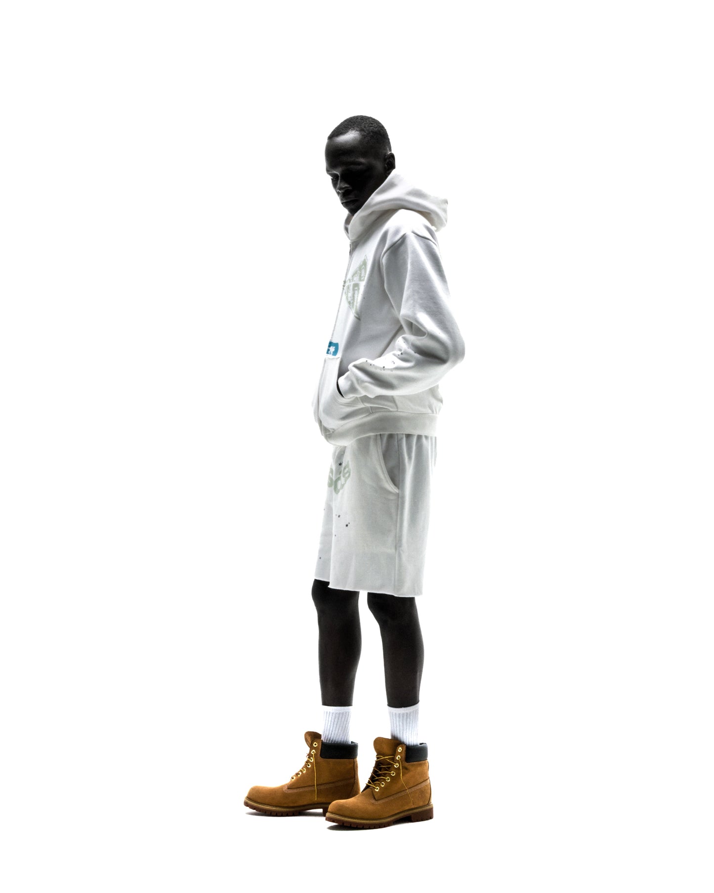 Model wearing a white 13oz cotton fleece T&F zip-up hoodie with scattered star print and matching shorts.