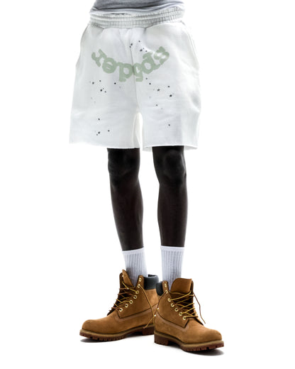 Model wears white T&F SWEATSHORT with "SP5DER" print, scattered stars, raw hem, and drawcord.