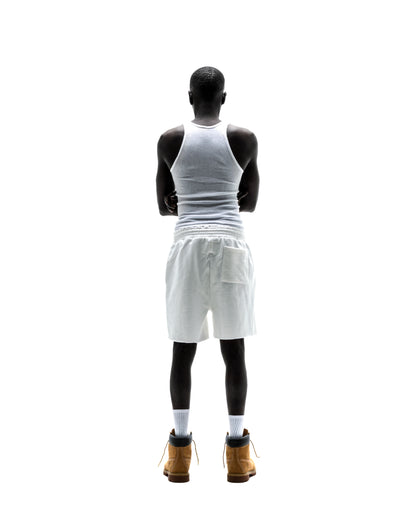 Model from behind wearing T&F SWEATSHORT, white 13oz cotton fleece shorts with back pocket and raw hem.