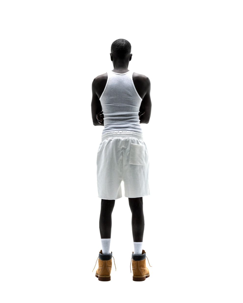 Model from behind wearing T&F SWEATSHORT, white 13oz cotton fleece shorts with back pocket and raw hem.