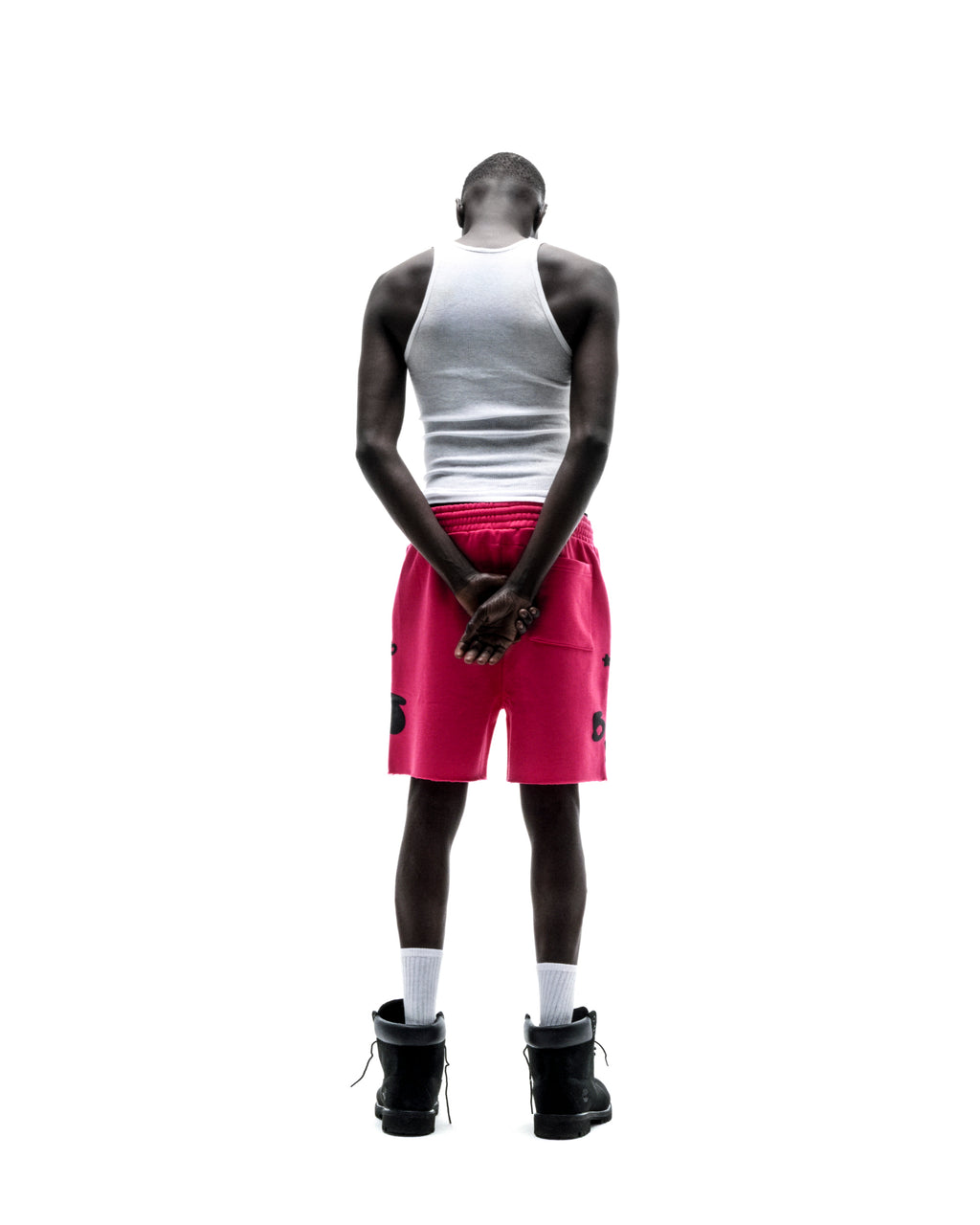 Model from behind wearing pink Beluga sweatshorts with black print, raw hem, and drawcord.