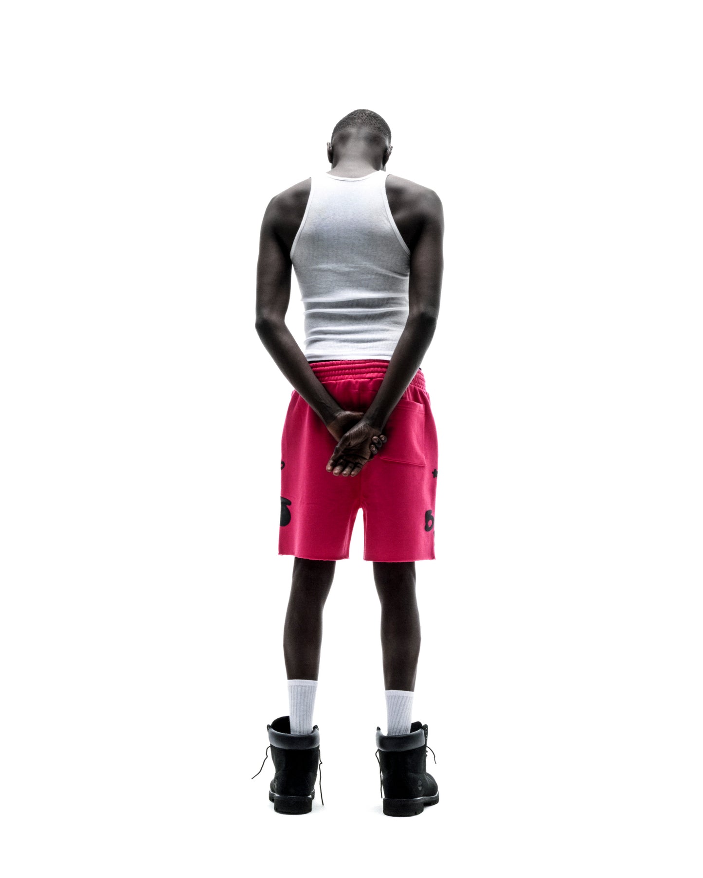 Model from behind wearing pink Beluga sweatshorts with black print, raw hem, and drawcord.