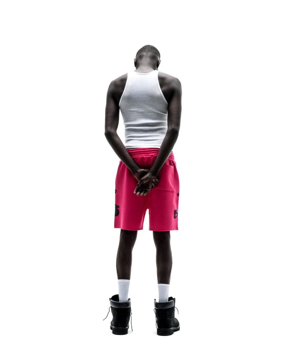 Model from behind wearing pink Beluga sweatshorts with black print, raw hem, and drawcord.