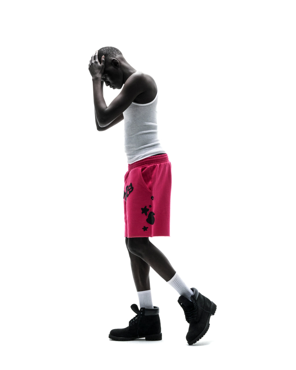 Model in pink Beluga print cotton fleece sweatshorts with raw hem, white tank top, and black boots.