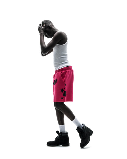 Model in pink Beluga print cotton fleece sweatshorts with raw hem, white tank top, and black boots.