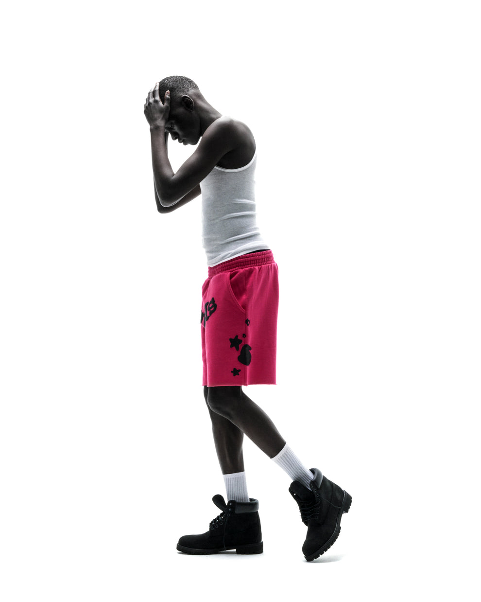Model in pink Beluga print cotton fleece sweatshorts with raw hem, white tank top, and black boots.
