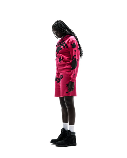 Model in a pink 13oz cotton fleece Beluga Zip Up hoodie and matching shorts with black puff print designs.