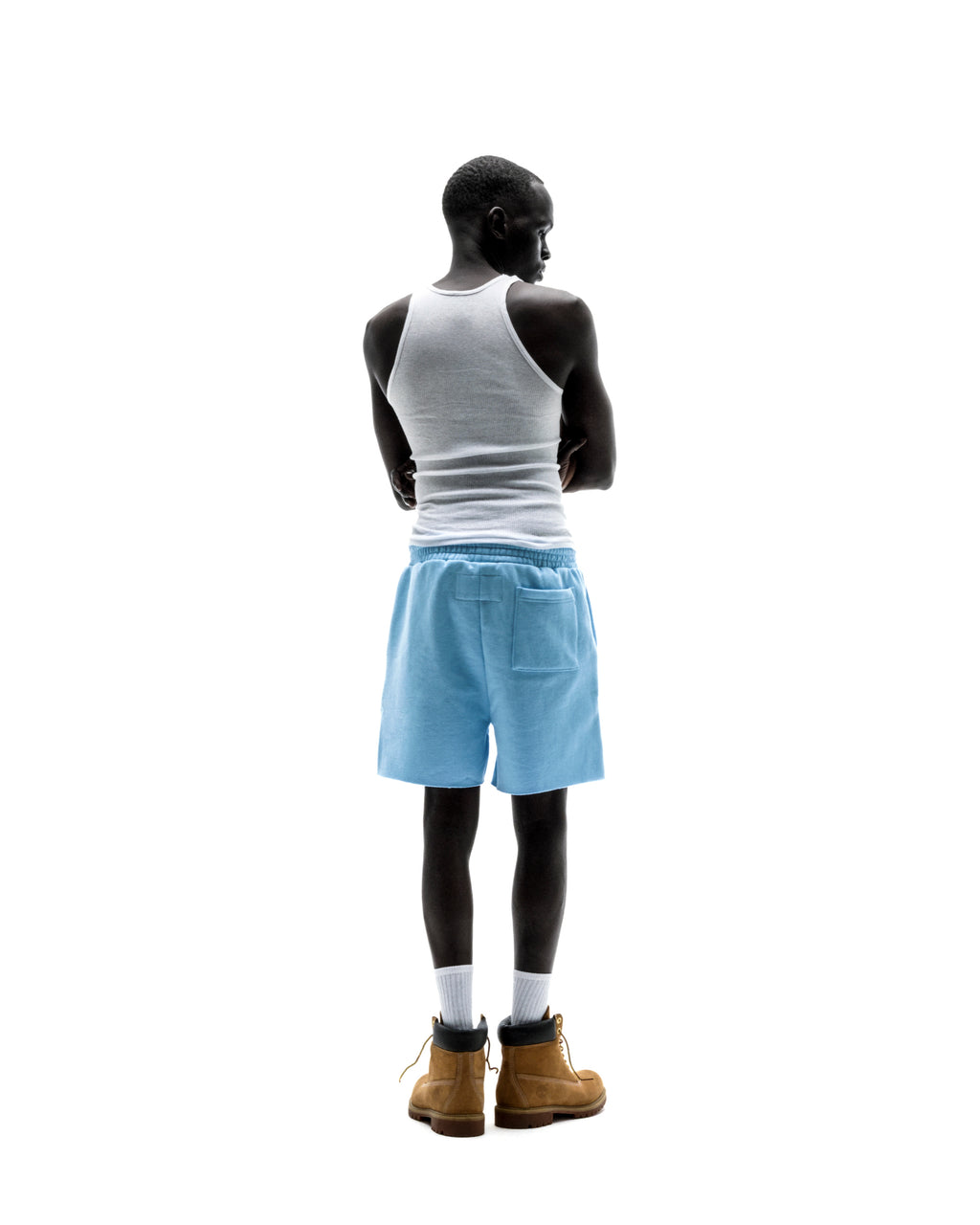 Model wearing light blue OG WEB SWEATSHORTS with back patch pocket, white tank top, and tan boots.