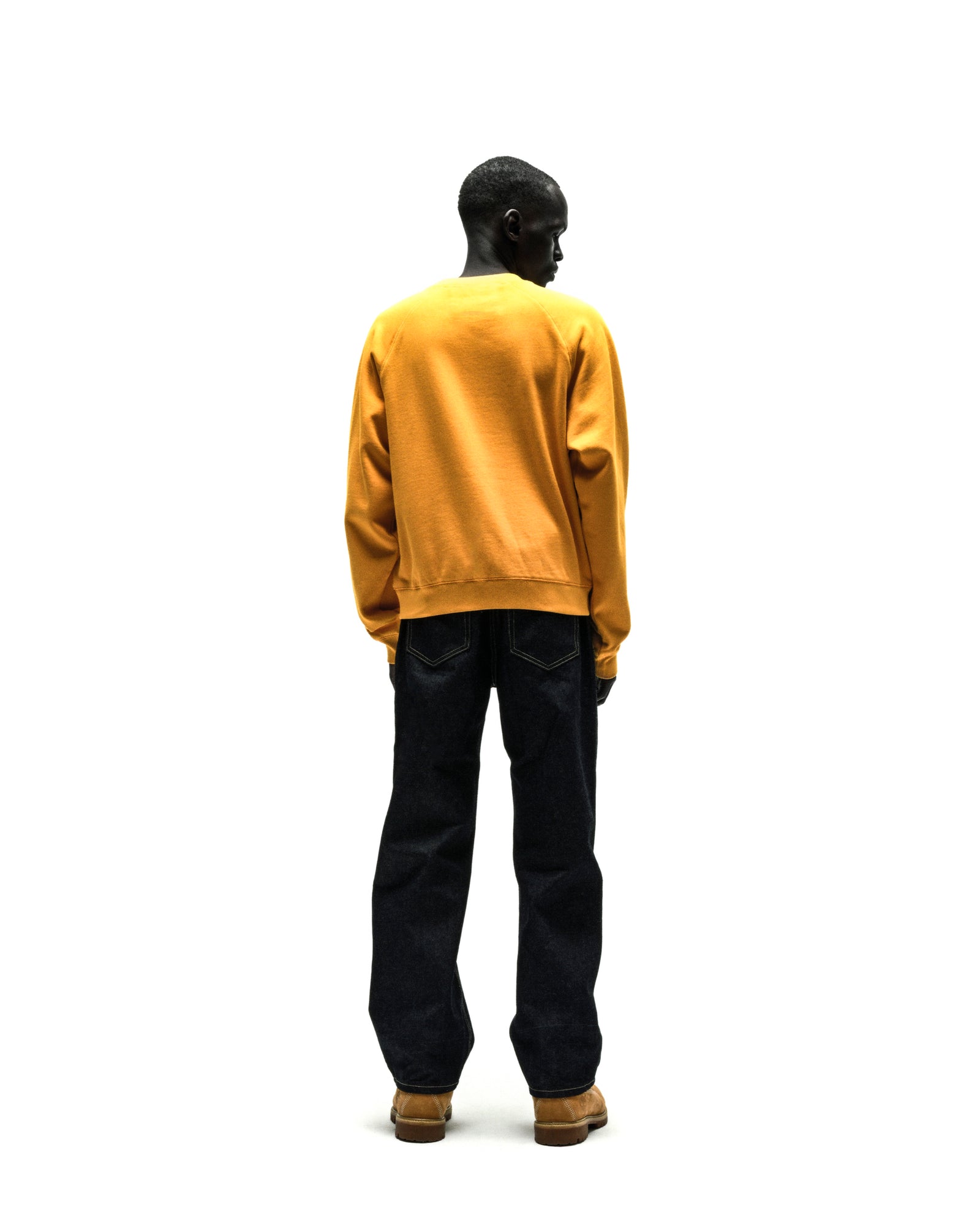 Mustard yellow 100% cotton brushed fleece raglan crewneck with ribbed hem and cuffs worn with dark denim jeans.