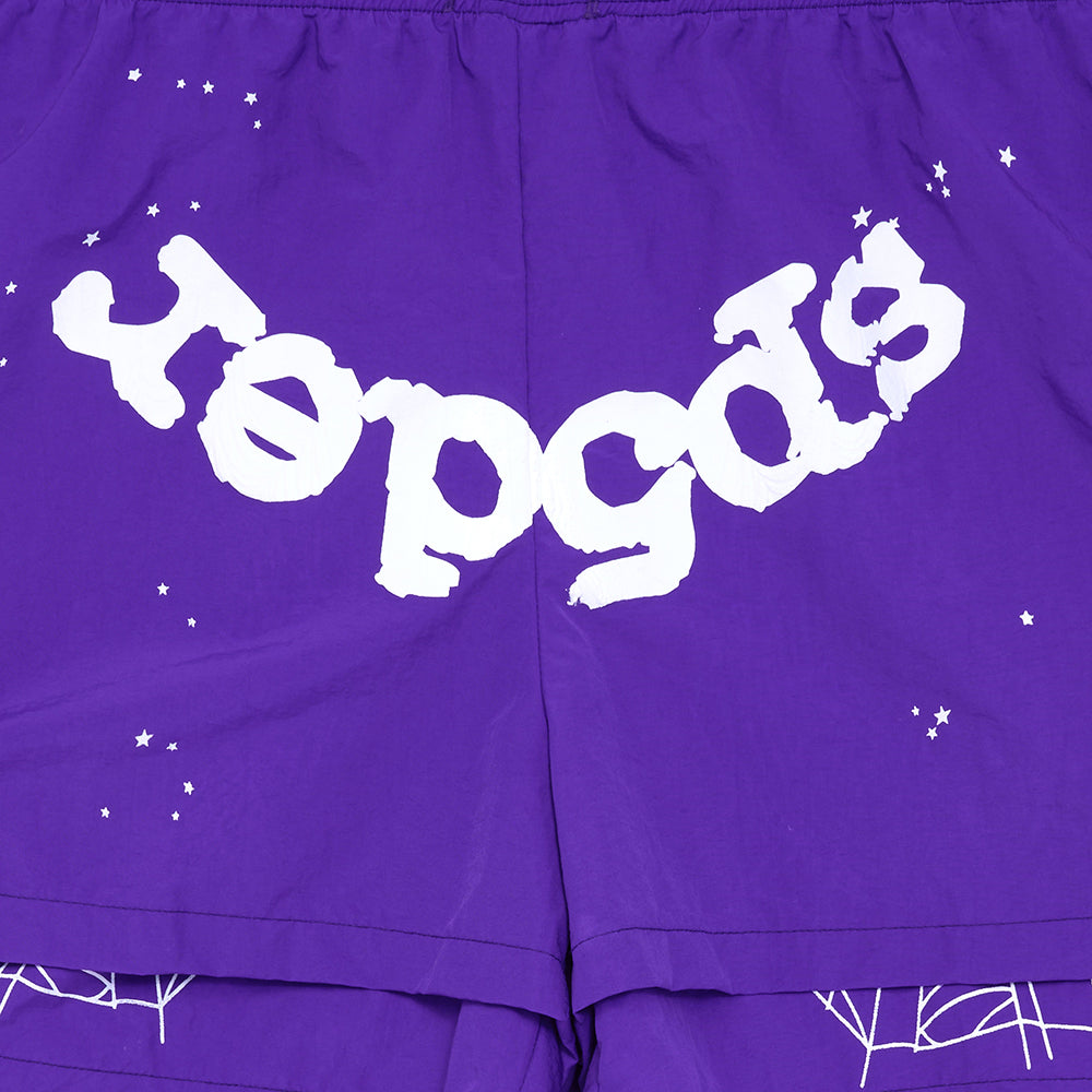 Purple nylon shorts with white "sp5der" text, web print, and scattered stars.