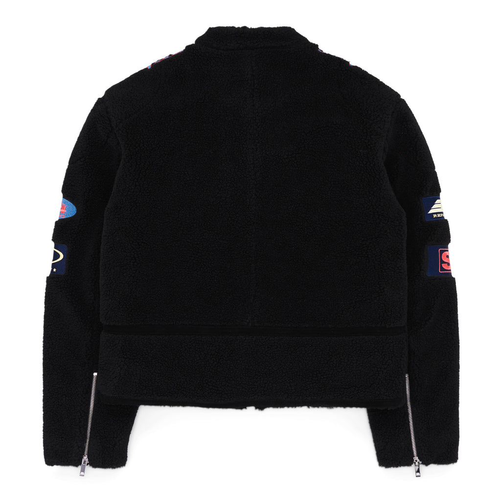 Black sherpa moto jacket with custom SP5DER patches, leather trim, zip closure, and sleeve zippers.