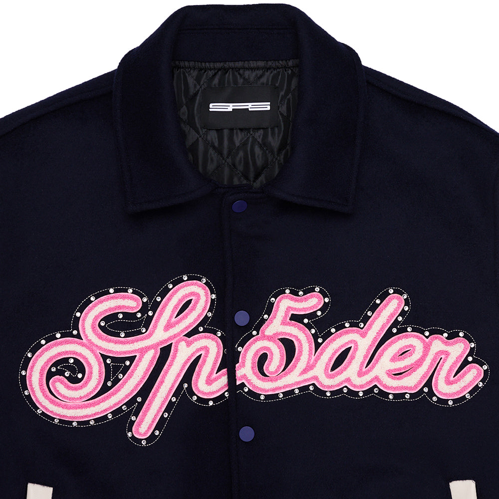 Navy wool varsity jacket with pink chenille "Sp5der" patch, jeweled stud outline, and quilted lining.