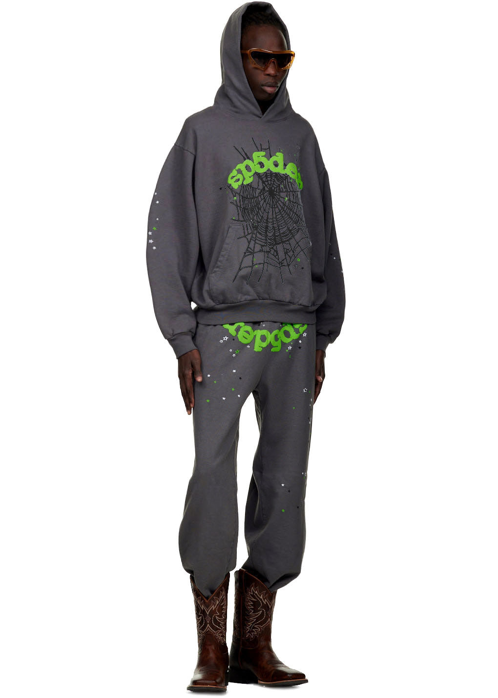 Male model in a gray WAIT WEB HOODIE and sweatpants with green SP5DER text, web print, and splatter details.