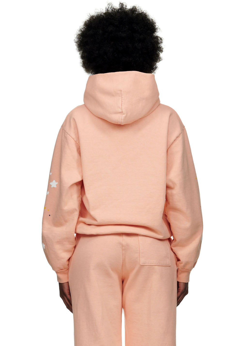 Back view of a female model wearing a peach SP5 Bellini hoodie and matching sweatpants.