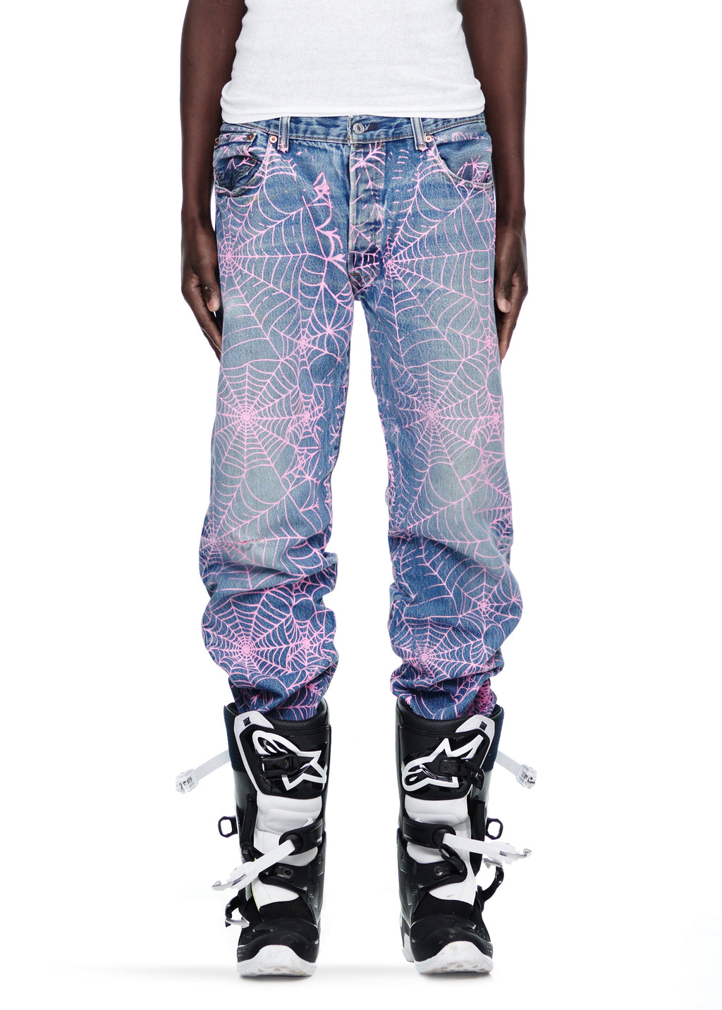 Vintage Levi's 501 denim jeans with all-over pink web print, worn by a person in black boots.