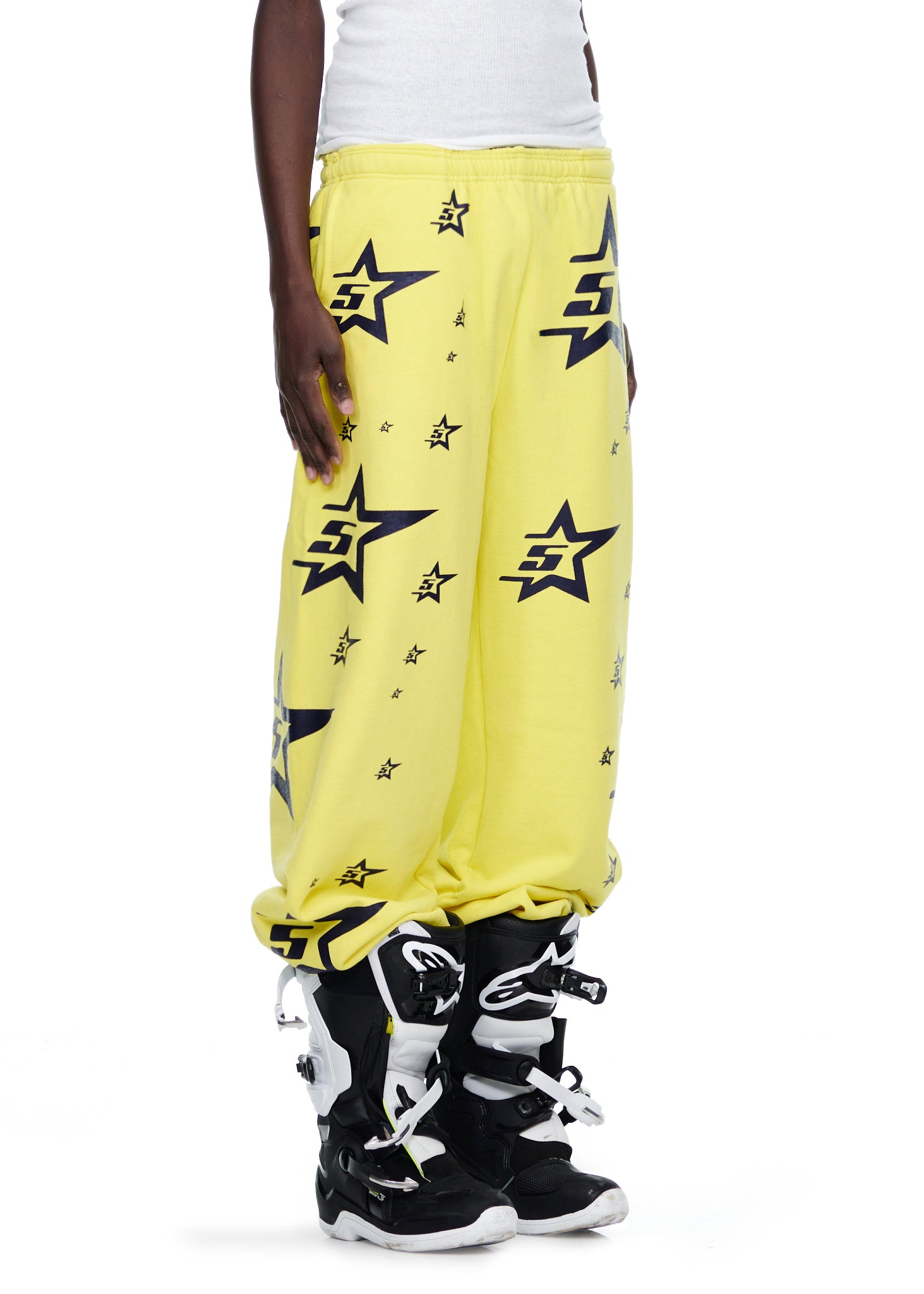 Yellow 5STAR SWEATPANT with all-over black star and "5S" prints, worn with motocross boots.