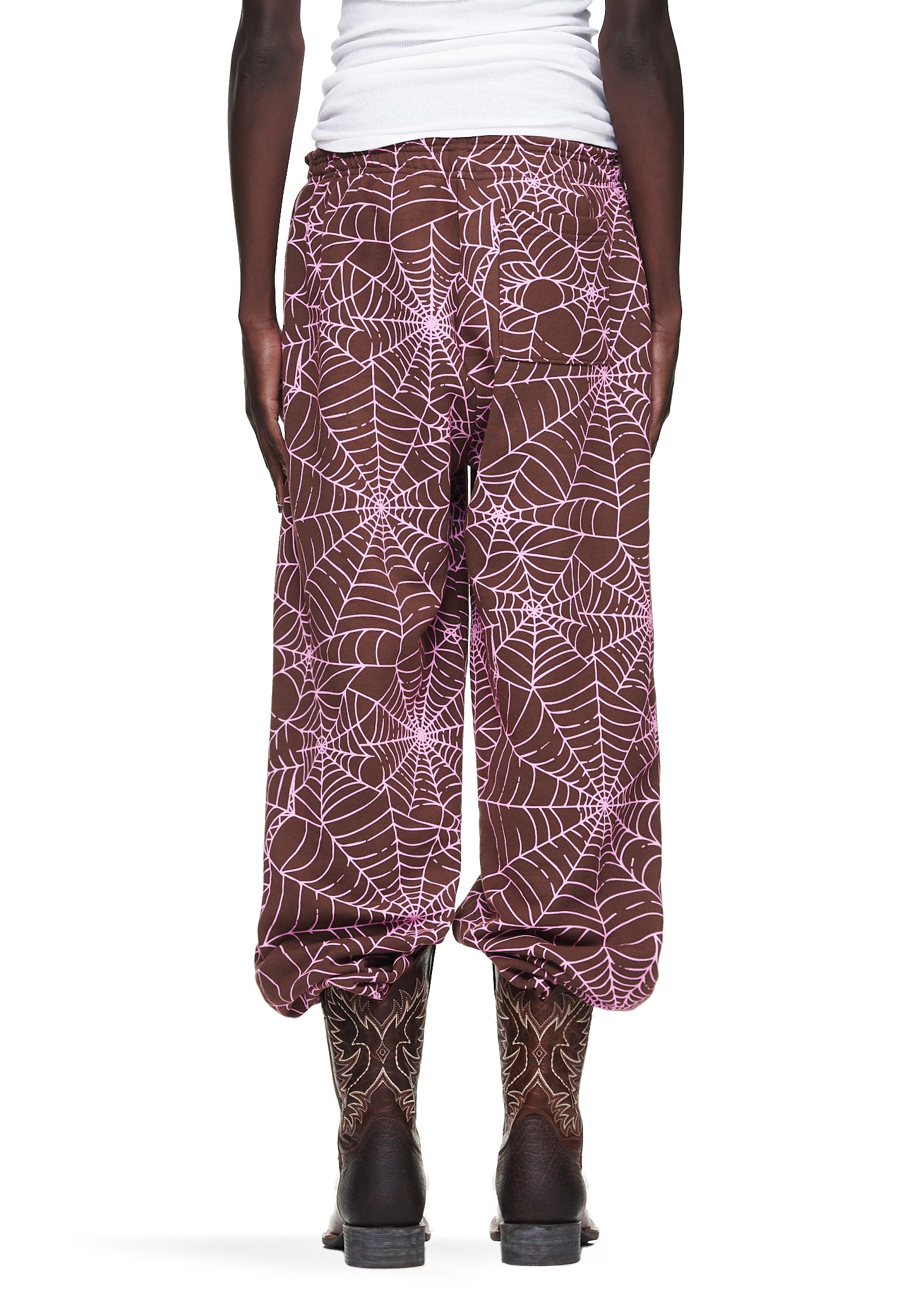 Brown fleece sweatpants with all-over pink cracked web print, worn by a male model.