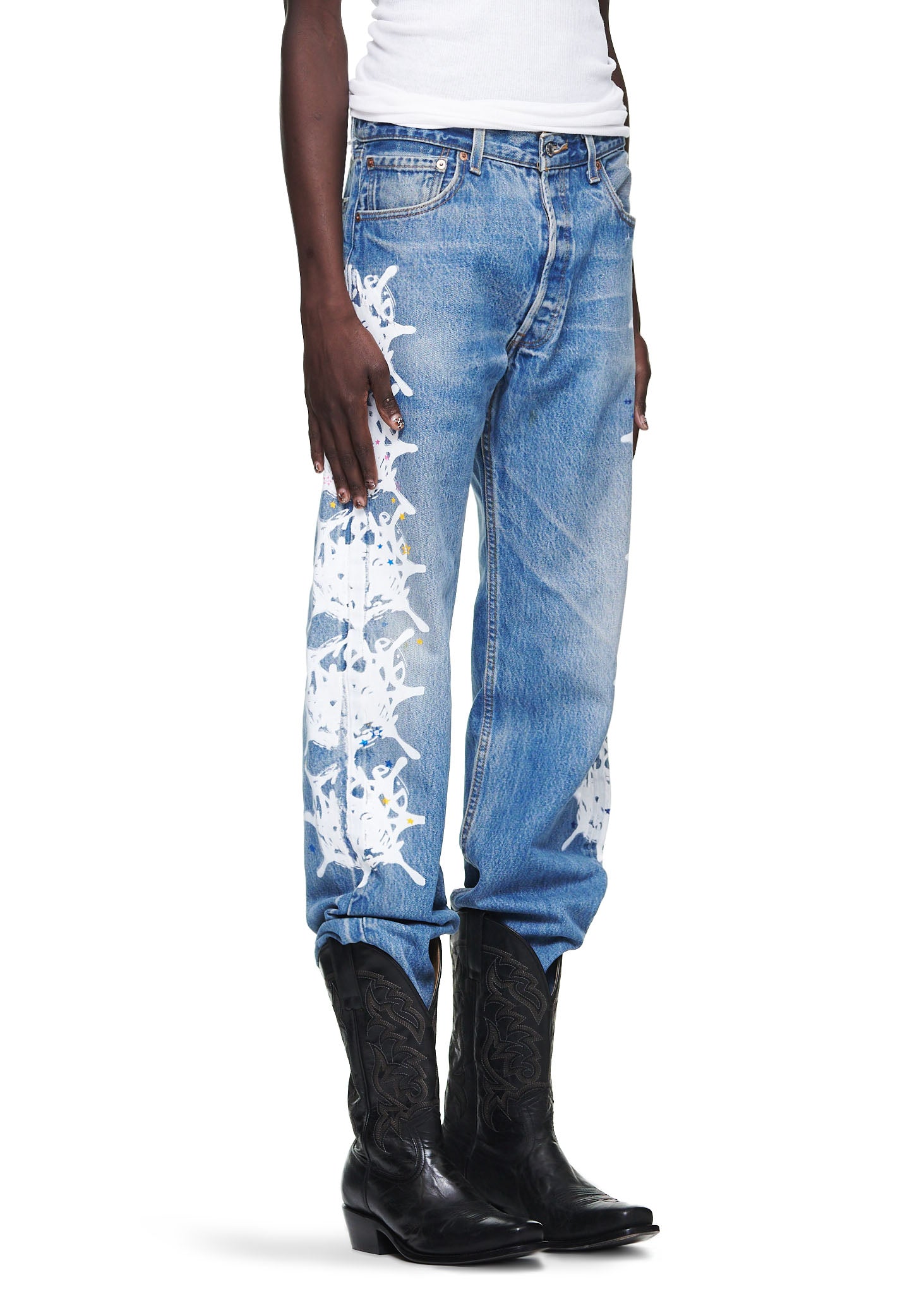 Vintage Levi's 501 denim jeans with white contrast web design down the leg, worn with black cowboy boots.