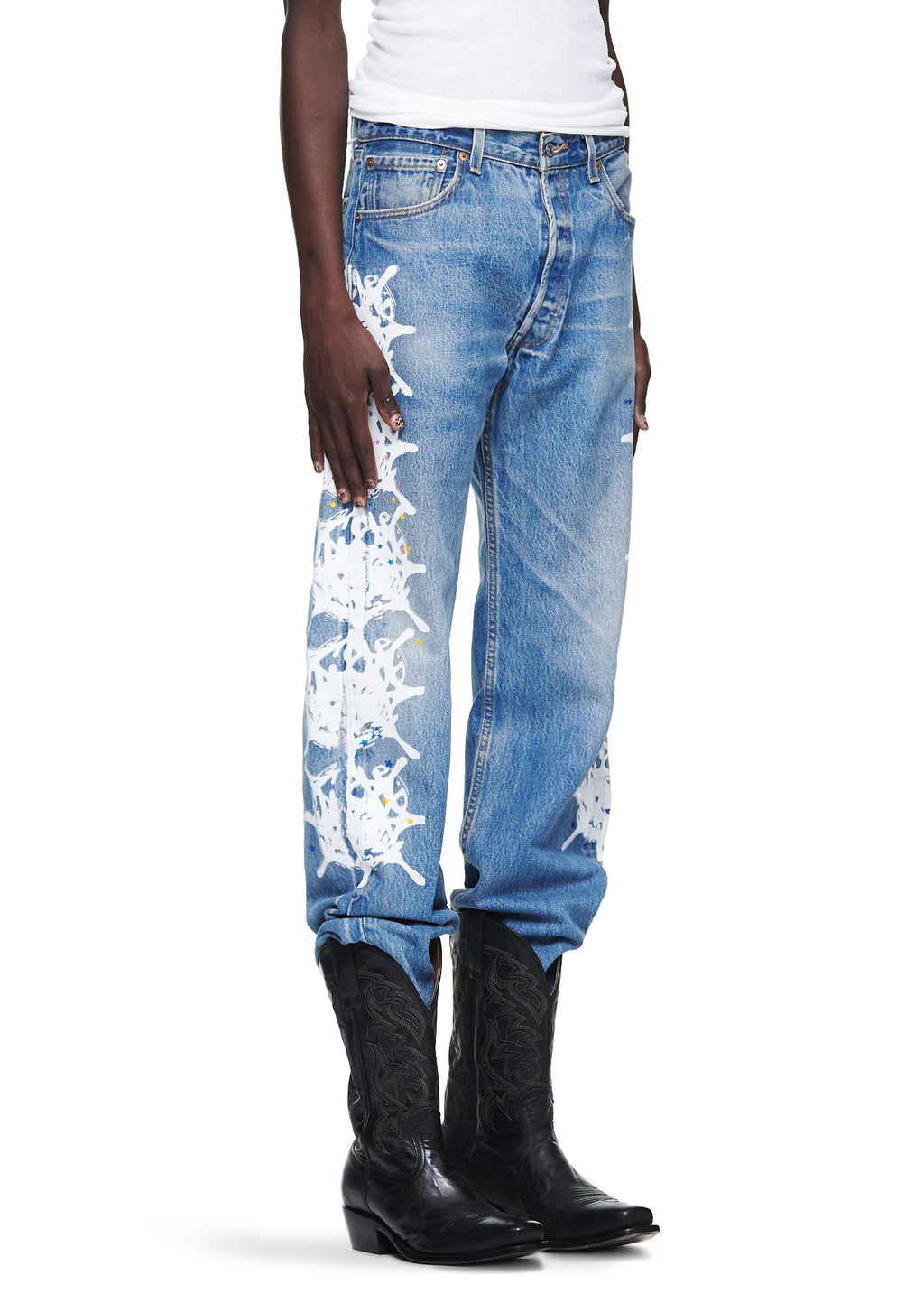 Vintage Levi's 501 denim jeans with white contrast web design down the leg, worn with black cowboy boots.
