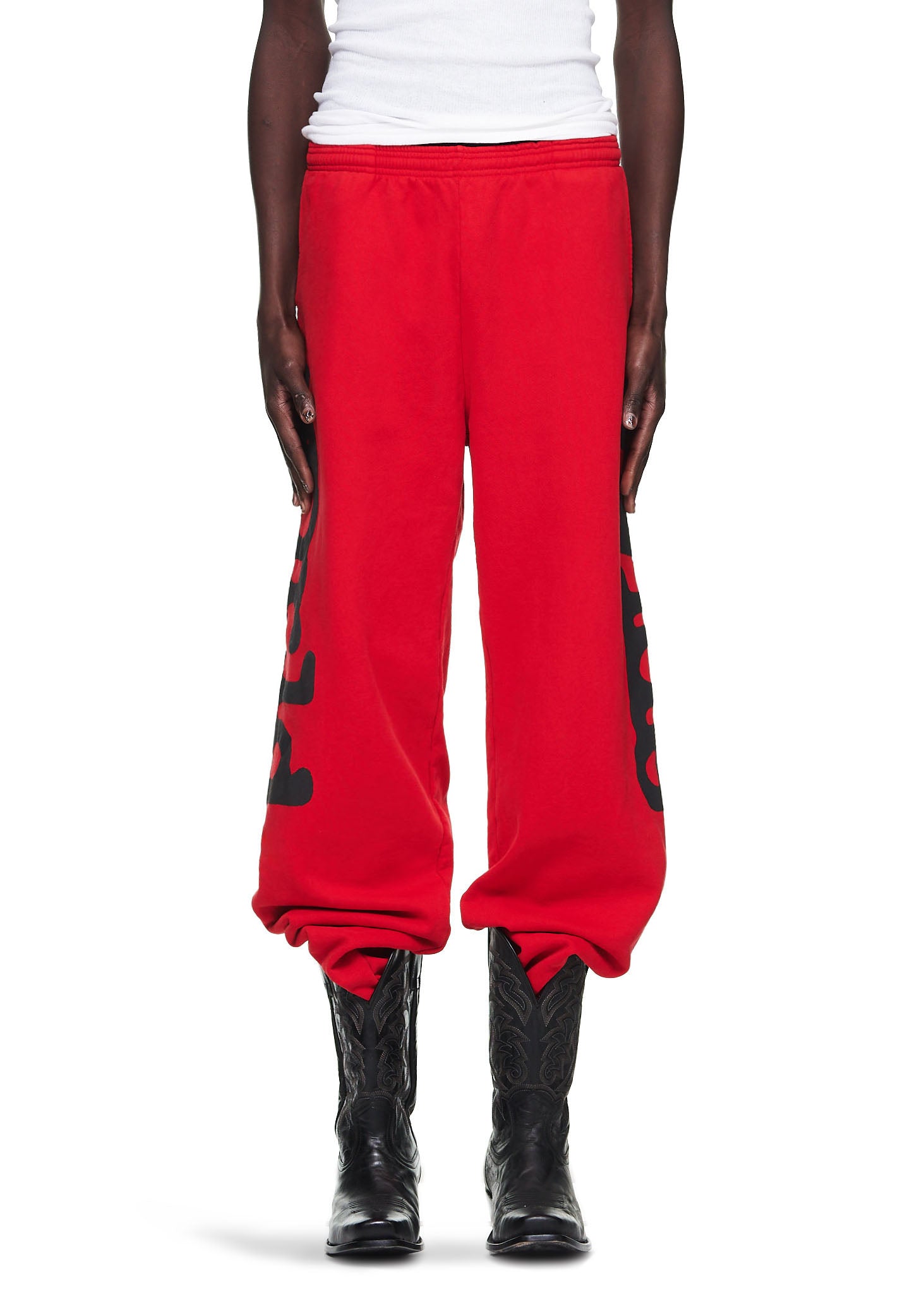 Red Beluga sweatpants with black 'Worldwide' puff print, worn by a male model in black cowboy boots.