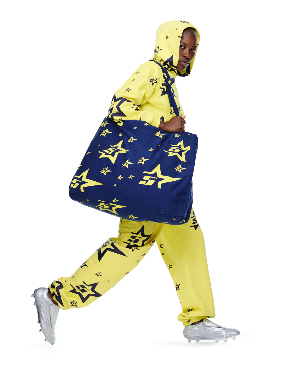 Model in yellow 5STAR print sweatsuit carrying a large navy 5STAR XL Tote bag.