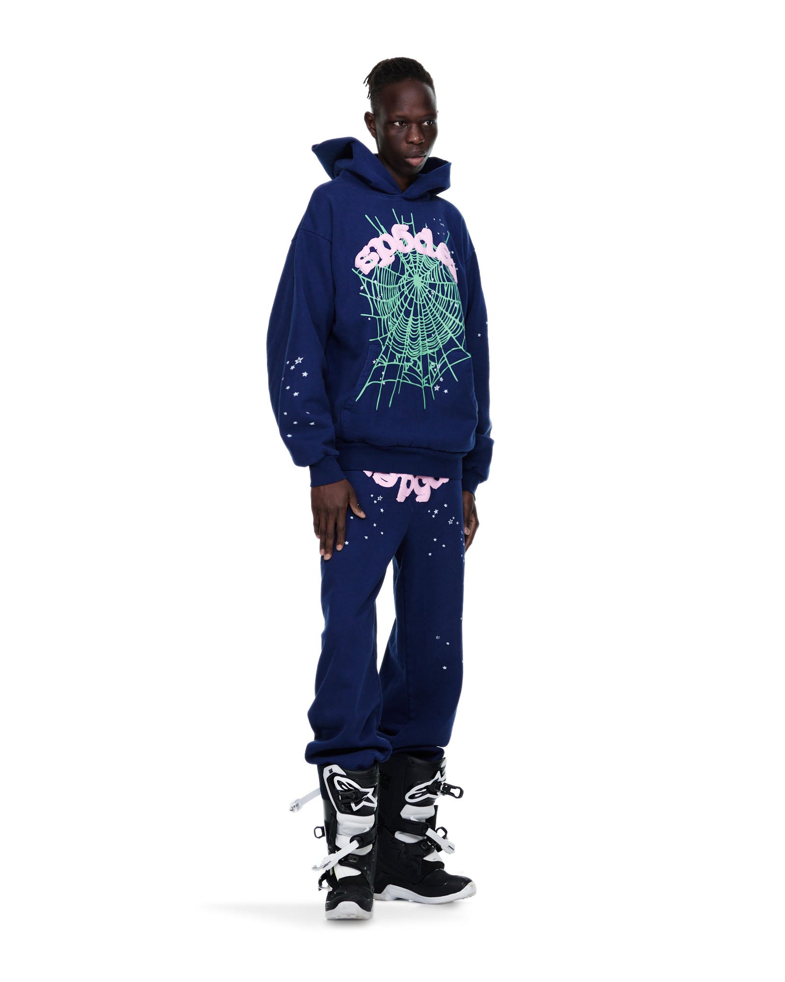 Male model in OG WEB HOODIE and sweatpants, navy 23oz fleece with green puff print spiderweb and pink "SP5DER" text.