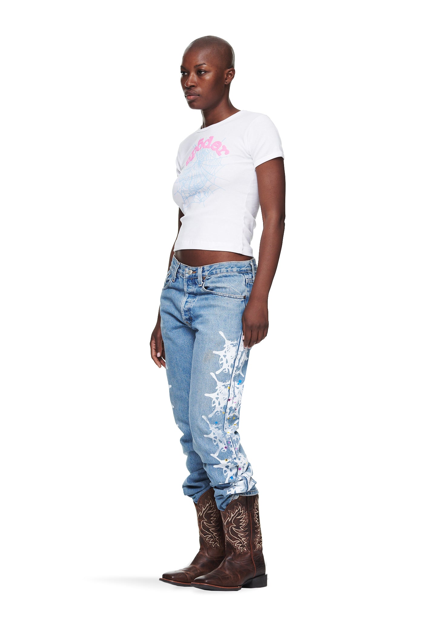 Female model in white cropped cotton tee with graphic web print and light wash jeans.