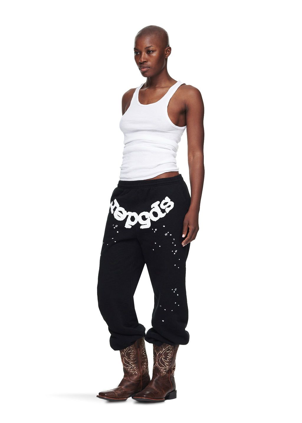 Female model in black OG WEB SWEATPANT with white puff print, scattered stars, and brown cowboy boots.