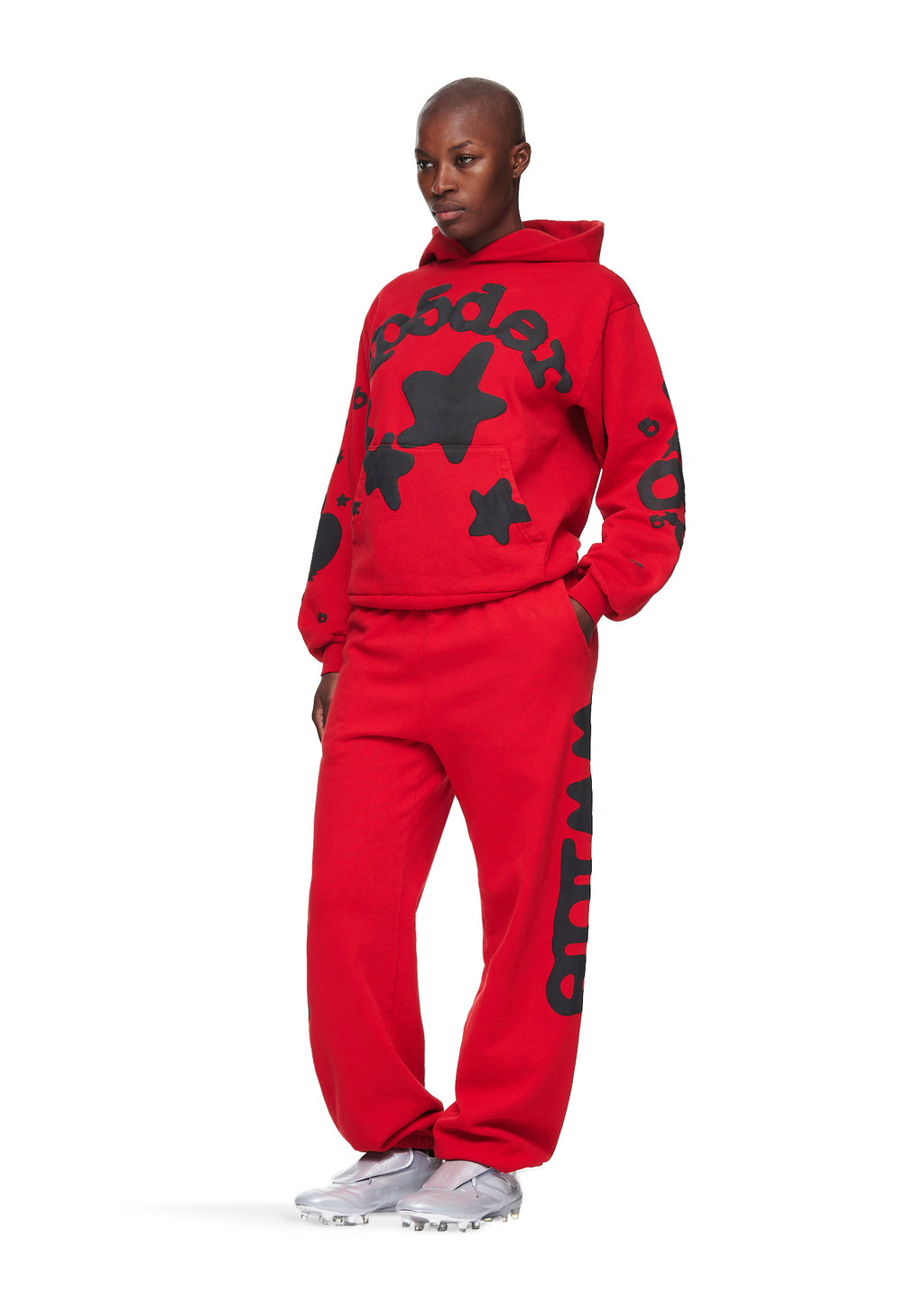 Male model in a red RED BELUGA HOODIE and sweatpants with black 'SP5DER' and star puff print.