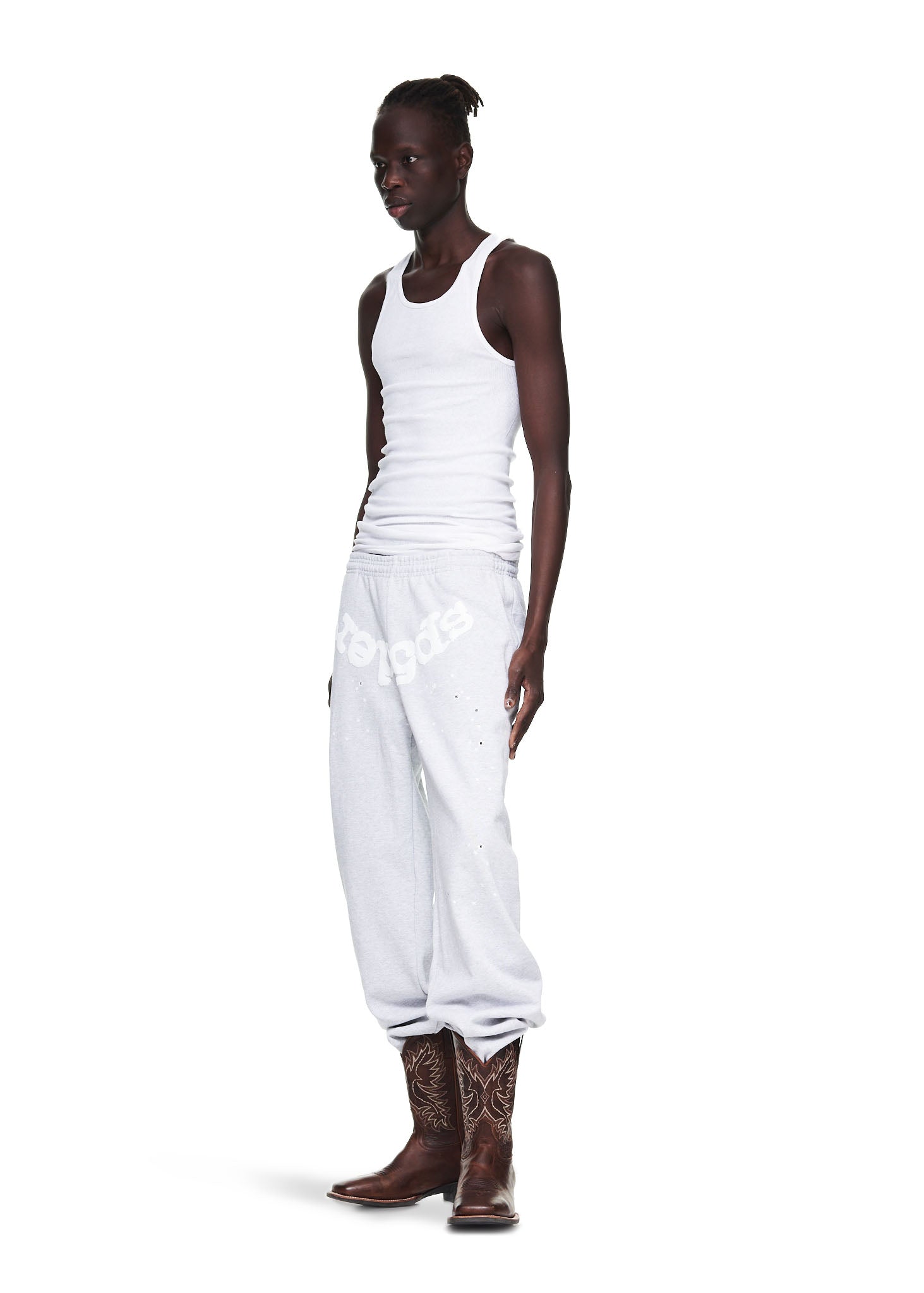 Male model in heather grey OG Web sweatpants with white puff print, paired with a white tank top and brown cowboy boots.
