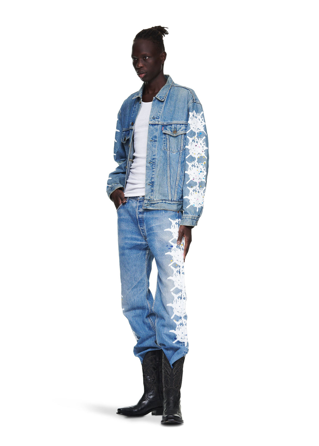 Male model in a vintage Levi's denim trucker jacket with white contrast web on arms, matching jeans, and black cowboy boots.
