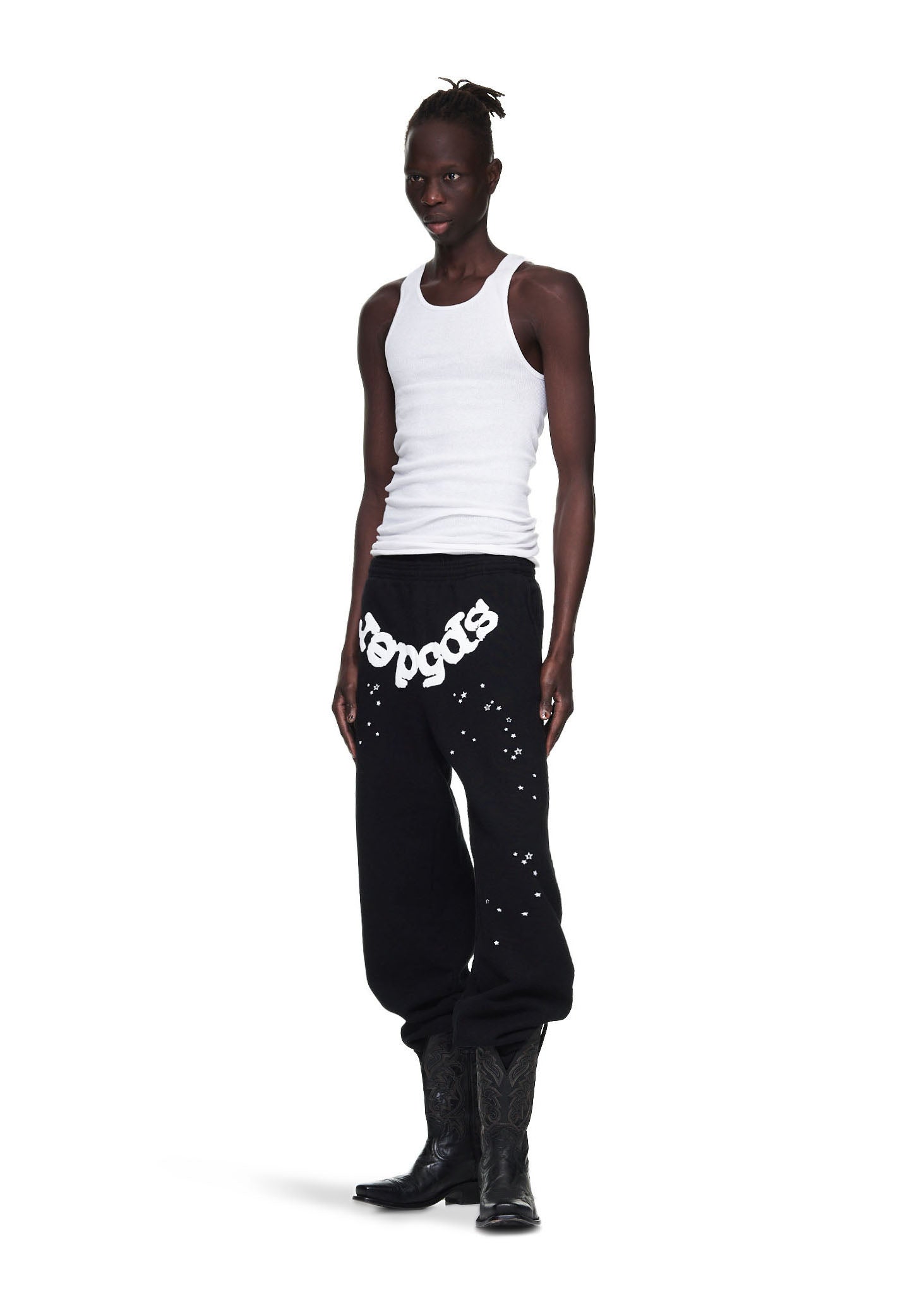 Male model in black OG Web Sweatpants with white puff print, stars, and cowboy boots.