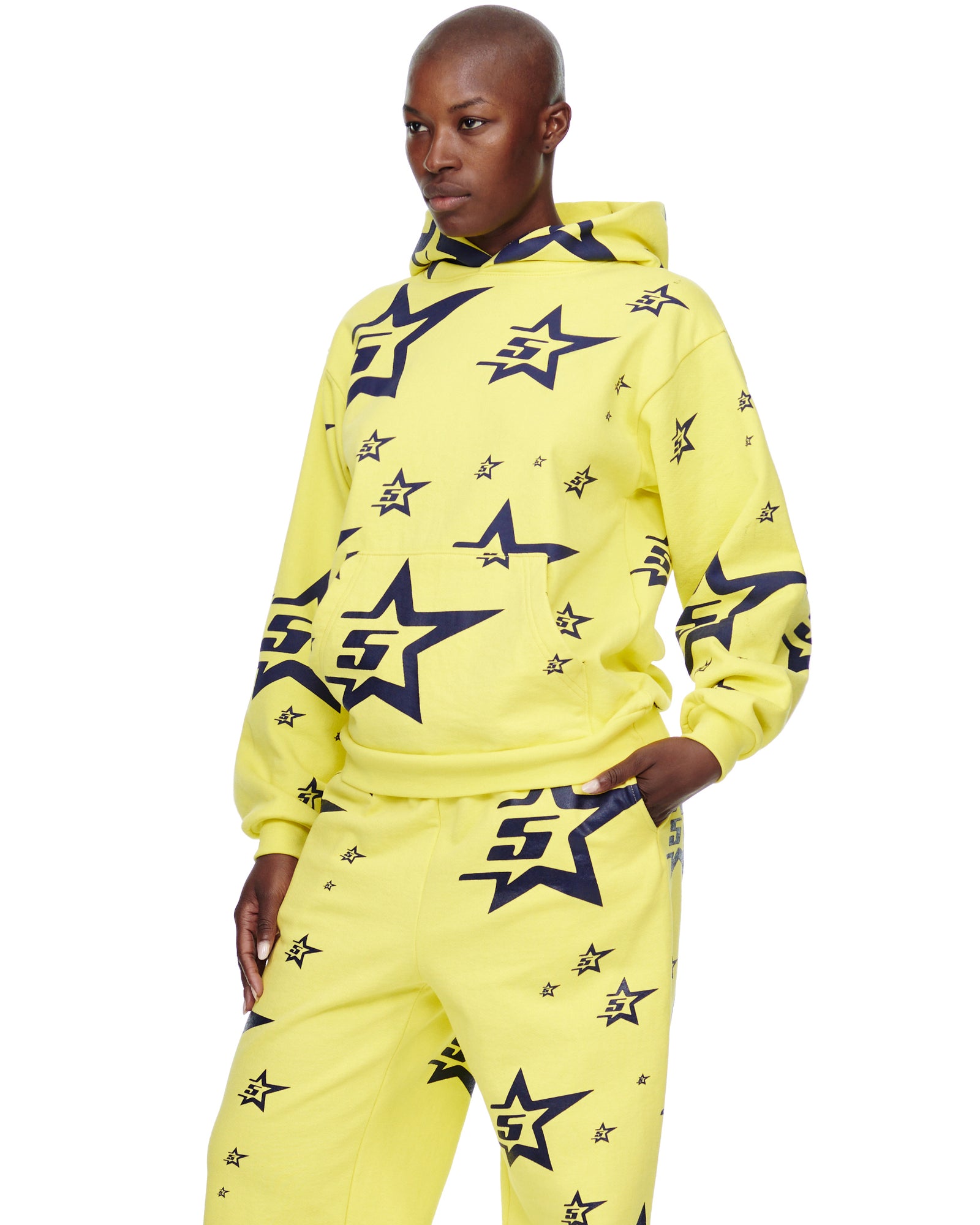 Model wearing a yellow 23oz fleece 5STAR HOODIE and matching sweatpants with all-over navy screen-printed star designs.
