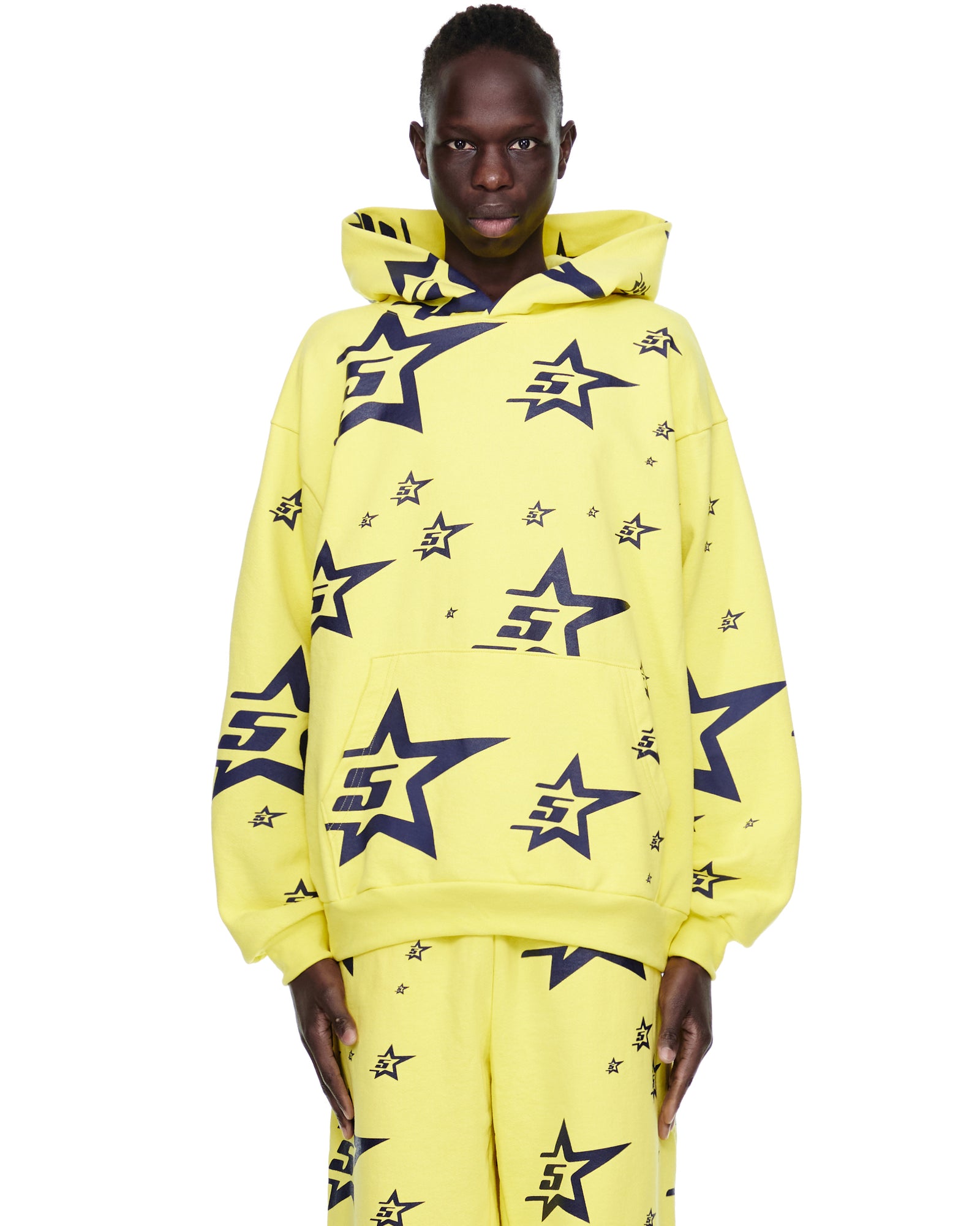 Yellow 5STAR HOODIE with all-over navy screen-printed star pattern, worn by a model.