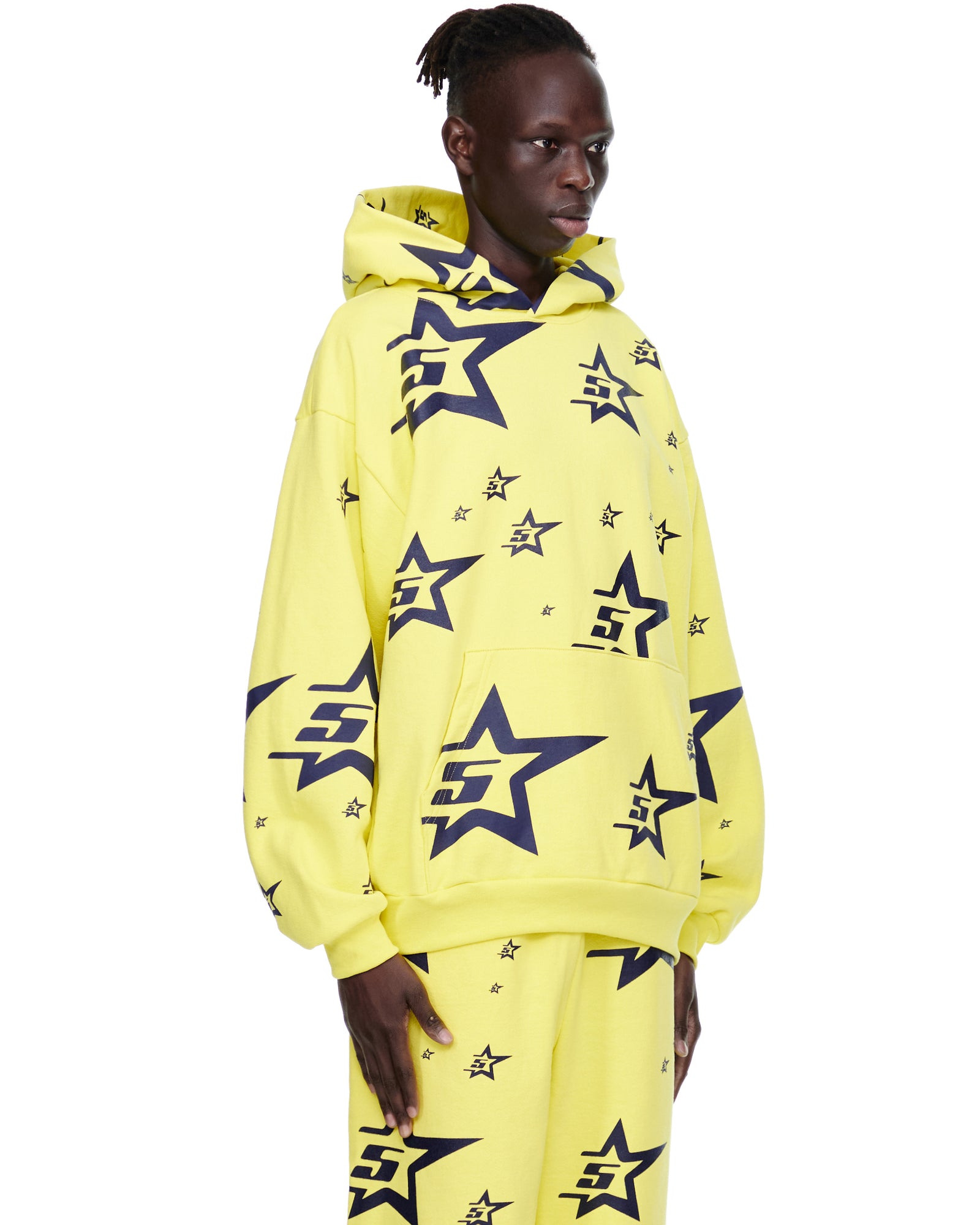 Model wearing a yellow 5STAR HOODIE with all-over navy screen-printed 5star graphics and matching sweatpants.