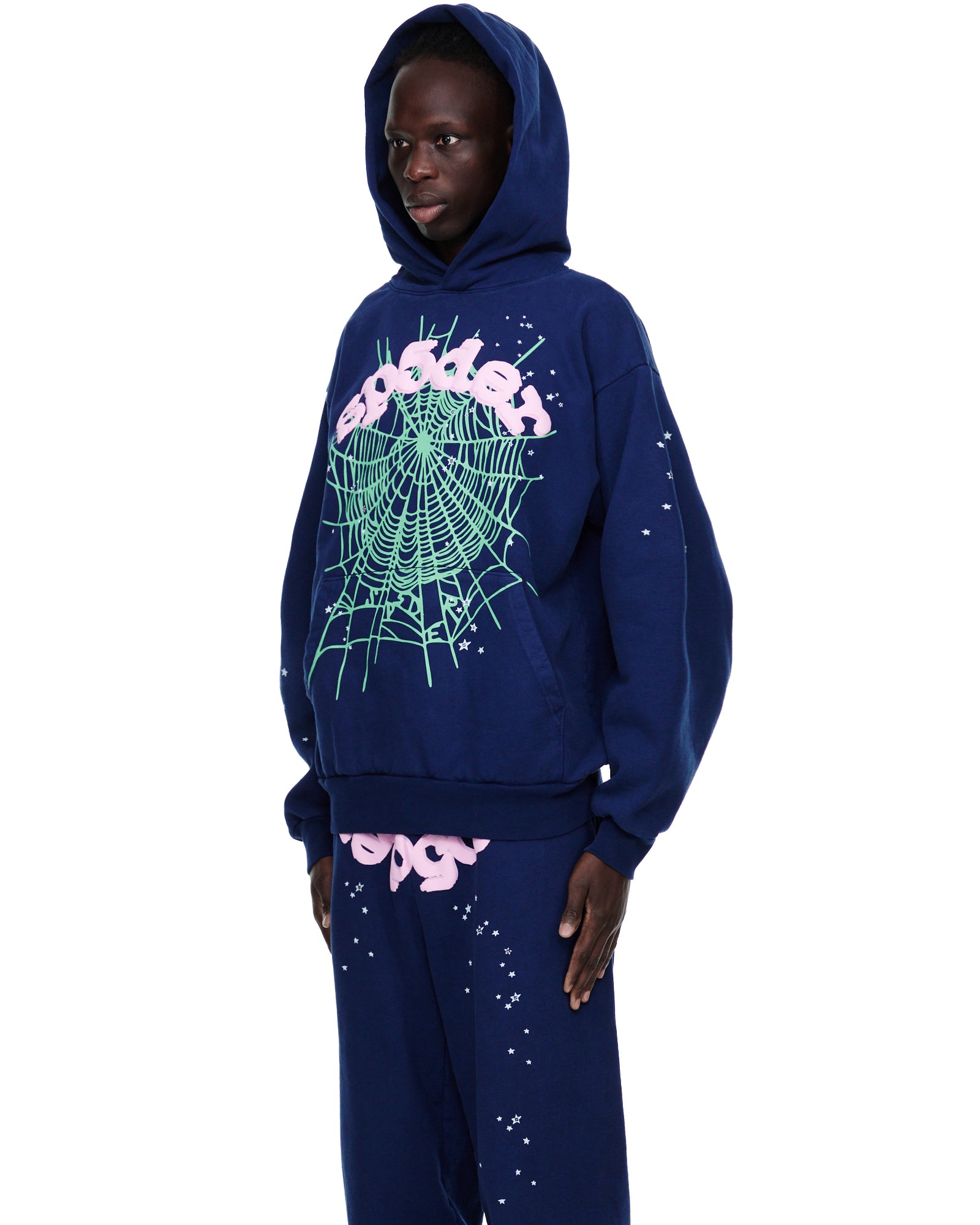 Male model in navy 23oz fleece OG WEB HOODIE and sweatpants with green web and pink SP5DER puff print.