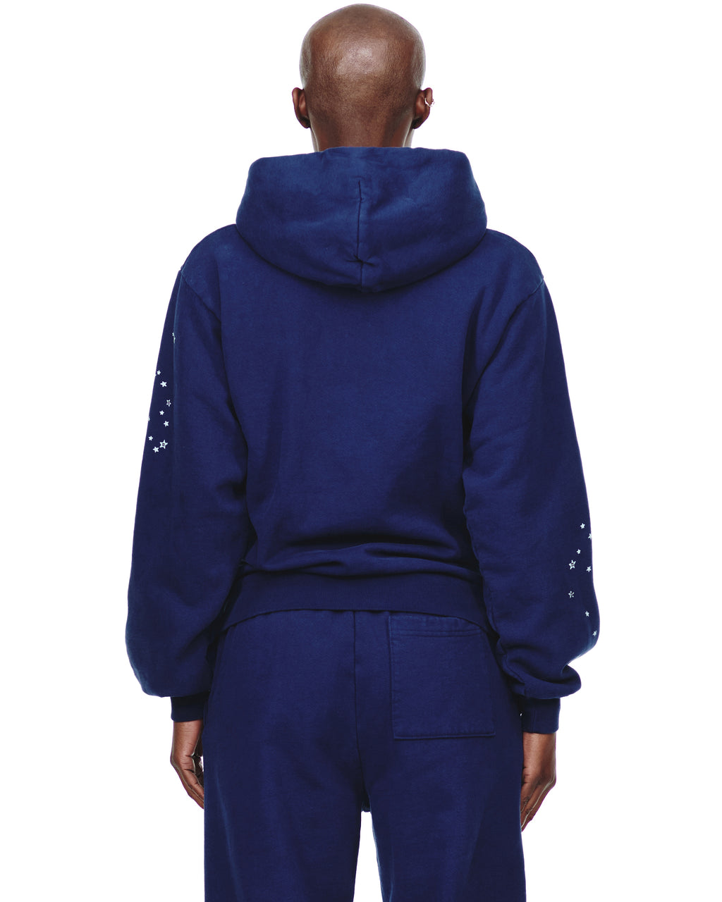 Back of a navy blue 23oz fleece hoodie with white star prints on the sleeves, paired with matching sweatpants.