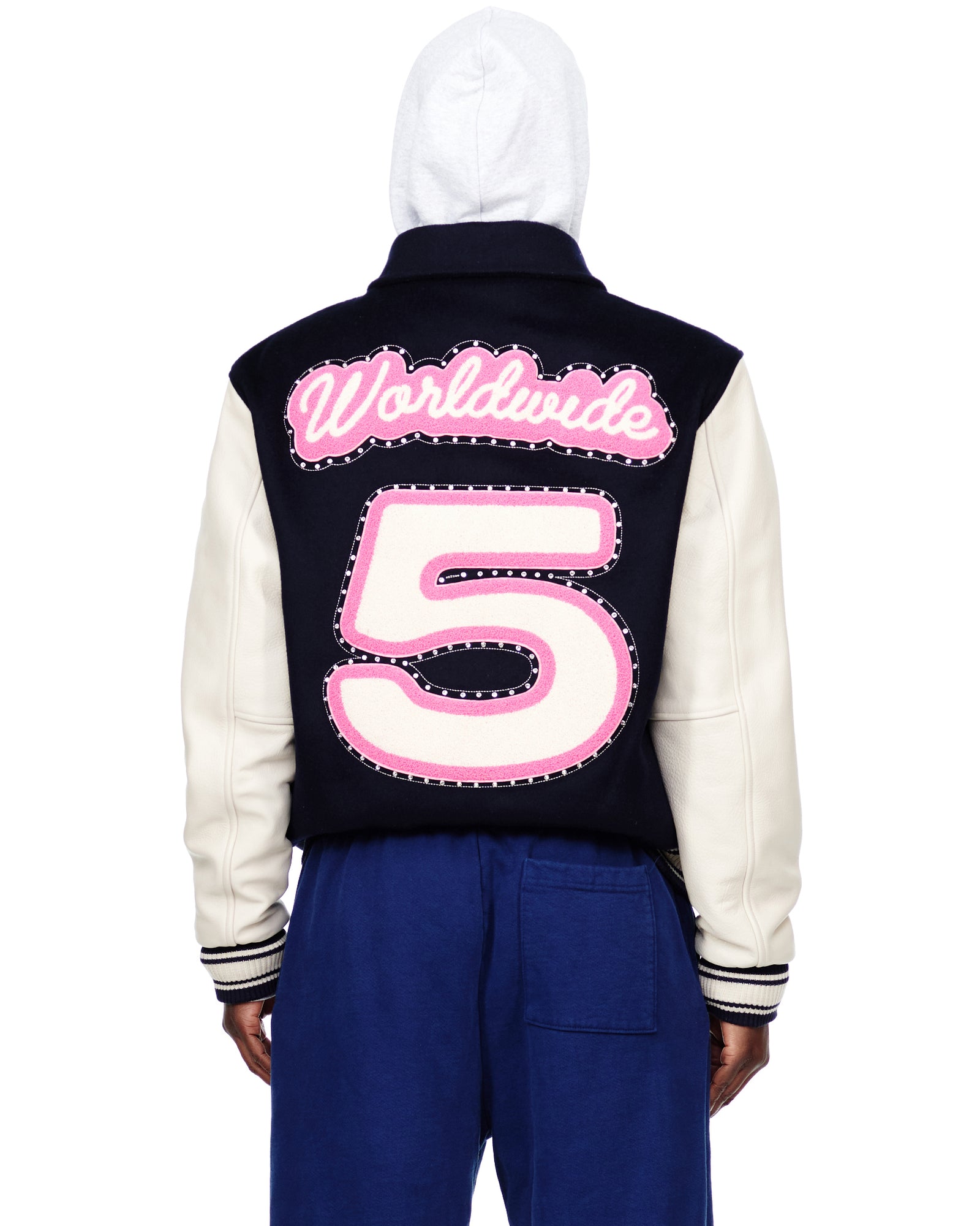 Navy wool varsity jacket with cream cowhide sleeves, pink "Worldwide 5" chenille patches, and striped cuffs.