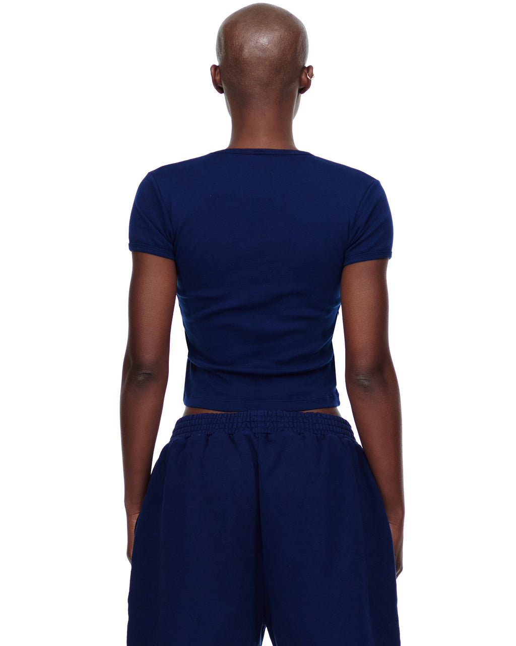 Back view of a female model wearing a navy blue cropped fitted cotton baby tee.