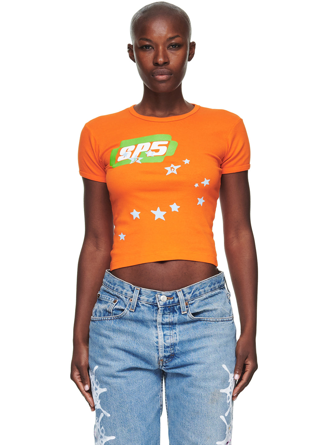 Female model in orange cropped cotton baby tee with "SPS" graphic and white stars.