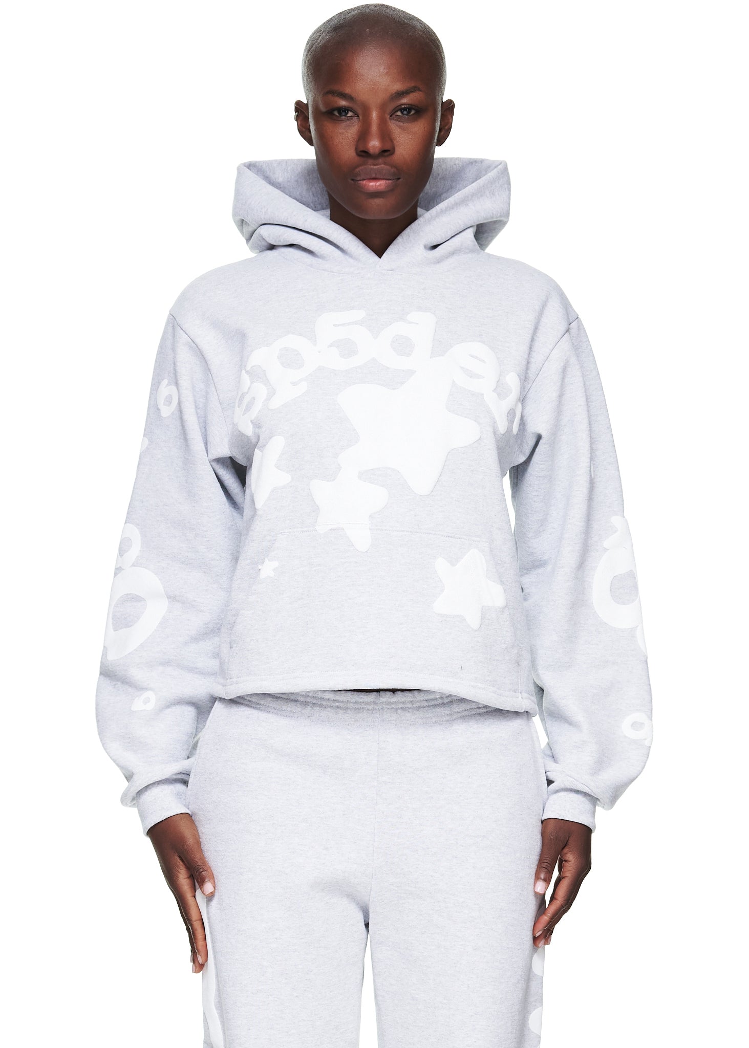 Women's cropped grey fleece hoodie with "SP5DER" and star puff print, paired with matching sweatpants.
